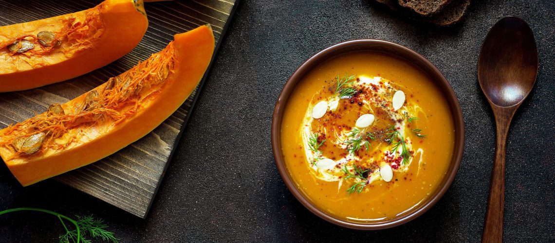 Roasted pumpkin and carrot soup with cream, seeds and fresh gree