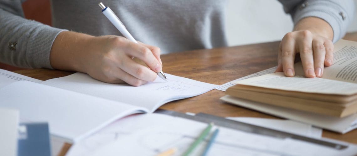 Student female hands performing a written task in a copybook with a pen, education concept photo. Close up
